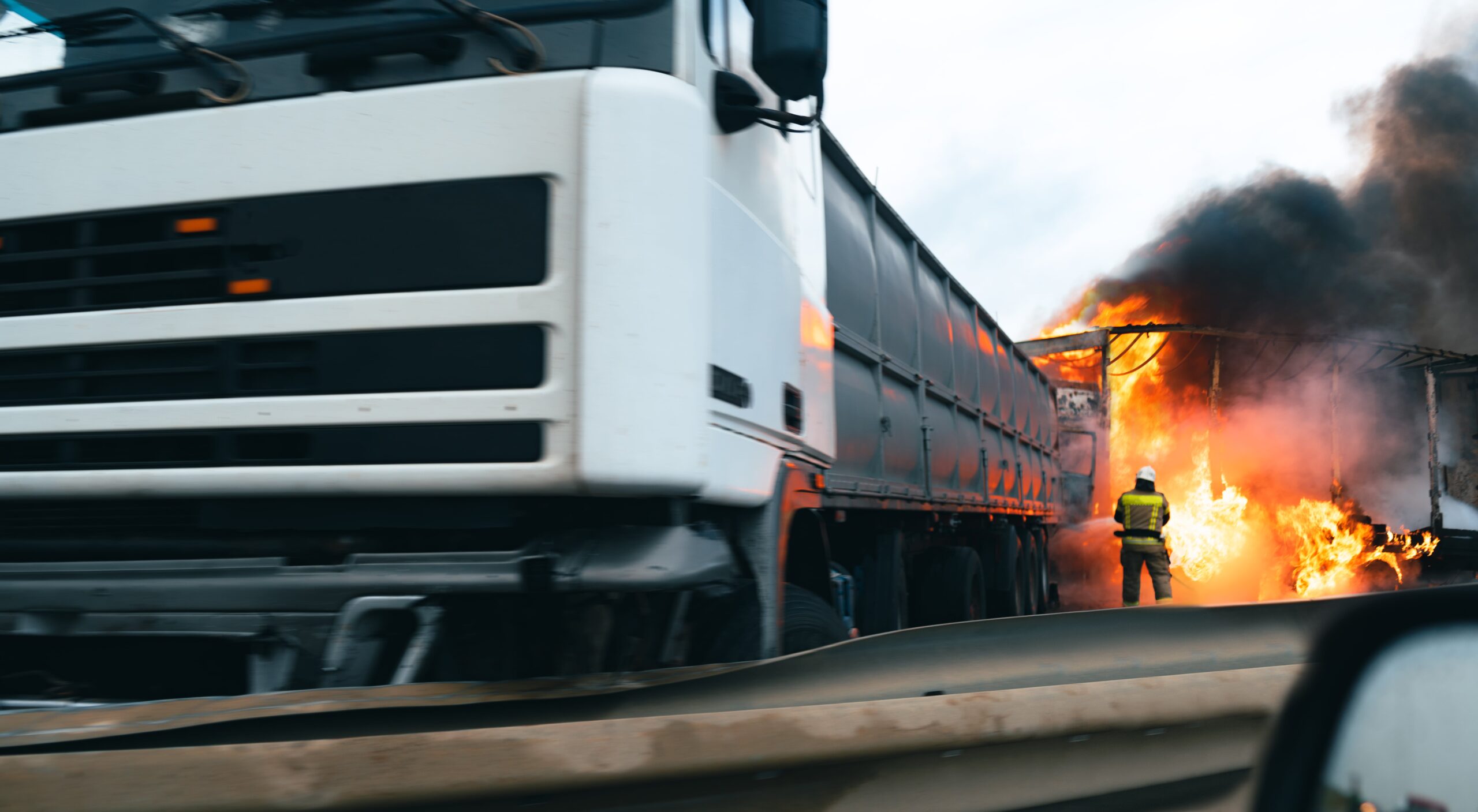 Truck crash on highway with burning vehicle, illustrating severe truck accidents and claims.