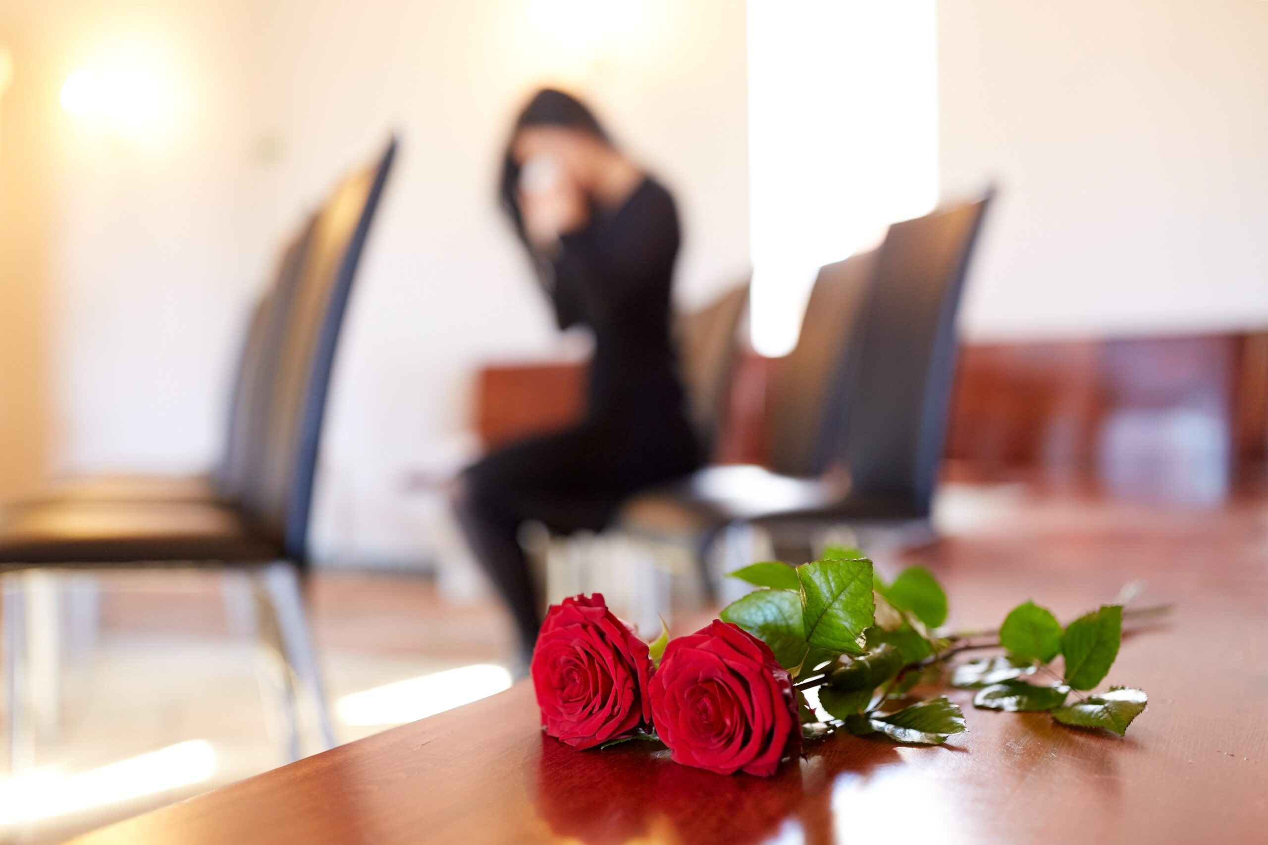 Woman crying at funeral with roses, showing wrongful death grief.
