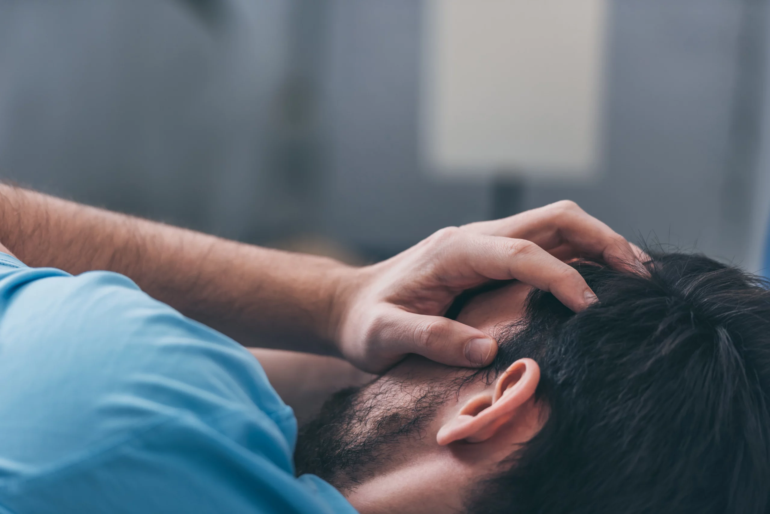 Stressed man lying down covering his face, showing signs of emotional pain or anxiety after injury